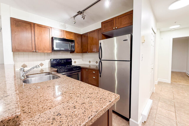 Bright kitchen with granite countertops, stainless steel appliances, and wooden cabinets. - 304-3637 West 17th Ave, Vancouver West Side