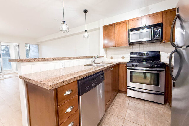 Bright kitchen with granite countertops, stainless steel appliances, and light wood cabinets. - 304-3637 West 17th Ave, Vancouver West Side