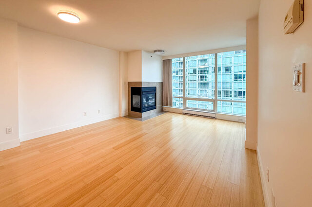 Spacious living room with hardwood floors, city view, and modern fireplace. - 706-499 Broughton, Vancouver Downtown