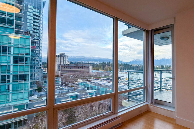 Spacious living room with large windows offering a stunning city view and marina, featuring hardwood floors and modern...
