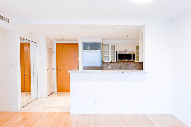 Bright kitchen with white cabinetry, granite countertops, and hardwood floors, offering a modern and inviting space.