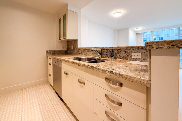 Bright kitchen with granite countertops and white cabinetry, featuring a modern sink and ample counter space. - 706-499 Broughton, Vancouver Downtown