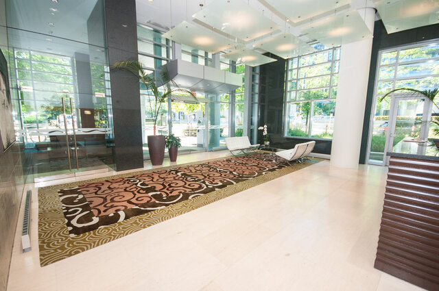 Spacious living room with modern decor, hardwood floors, and large windows offering a city view. - 706-499 Broughton, Vancouver Downtown