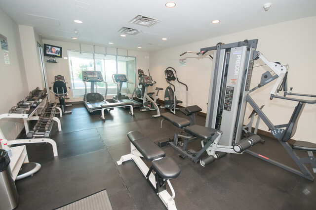 Spacious gym with cardio machines, weight racks, and a Precor machine. - 706-499 Broughton, Vancouver Downtown