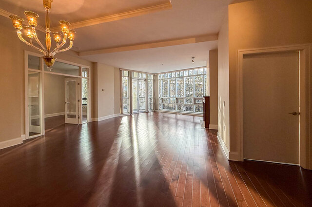 Spacious living room with hardwood floors and large windows, perfect for relaxation. - 301-605 Clyde Ave, West Vancouver