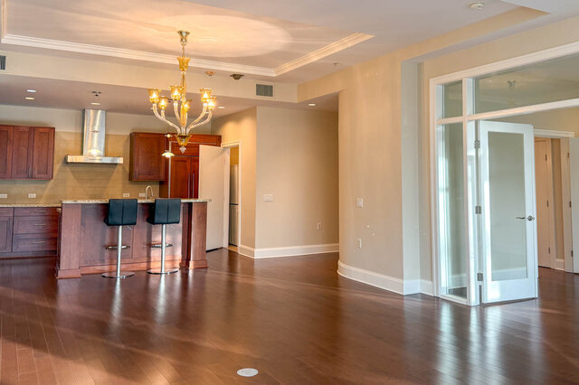 Spacious open-concept living room with hardwood floors and a modern chandelier. - 301-605 Clyde Ave, West Vancouver
