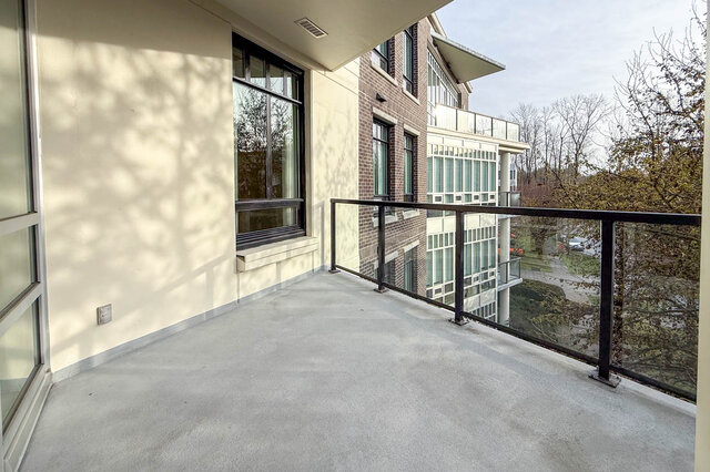 Spacious balcony with modern railings and views of trees. - 301-605 Clyde Ave, West Vancouver