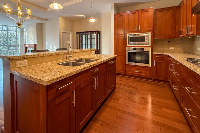 Bright kitchen with granite countertops, hardwood floors, and stainless steel appliances. - 301-605 Clyde Ave, West Vancouver