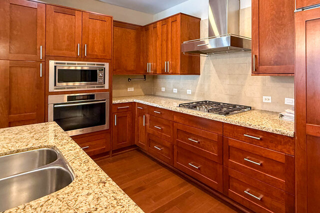 Bright kitchen with granite countertops, stainless steel appliances, and hardwood floors. - 301-605 Clyde Ave, West Vancouver