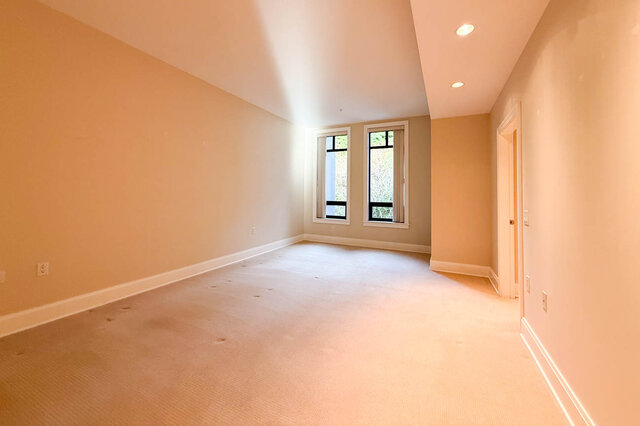 Spacious den with carpeted floor, large windows, and neutral walls. - 301-605 Clyde Ave, West Vancouver