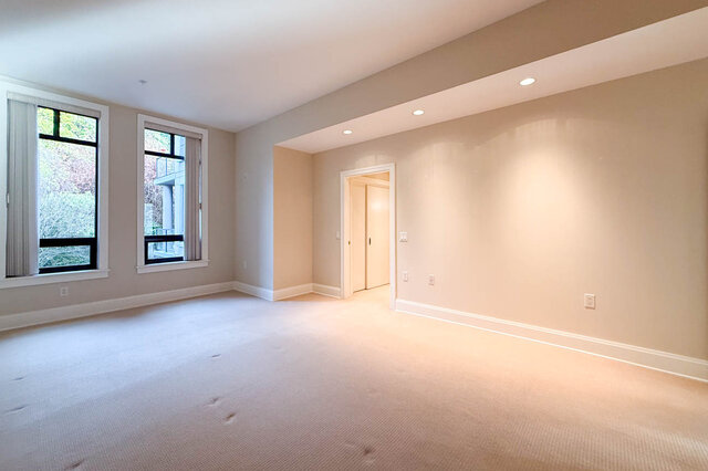 Spacious den with carpeted floor, large windows, and recessed lighting. - 301-605 Clyde Ave, West Vancouver