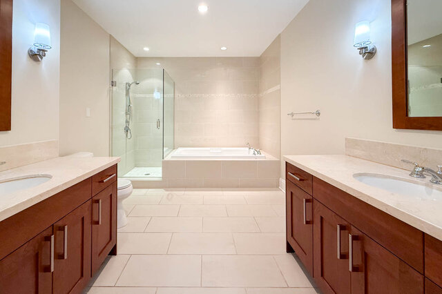Spacious bathroom with dual vanities, marble countertops, and a walk-in shower. - 301-605 Clyde Ave, West Vancouver