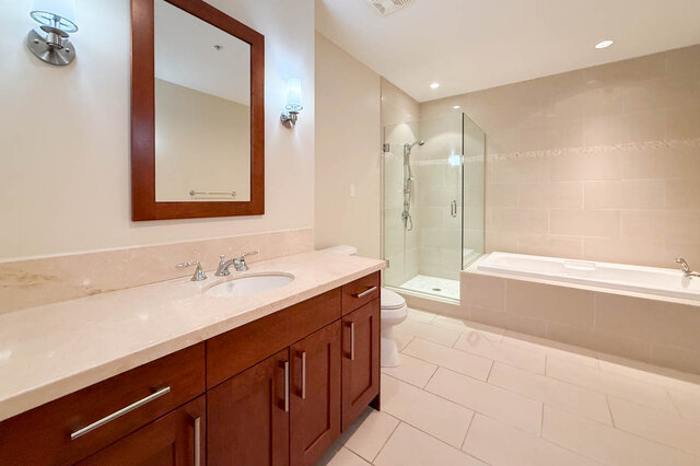 Spacious bathroom with dual vanity, marble countertops, and a walk-in shower. - 301-605 Clyde Ave, West Vancouver