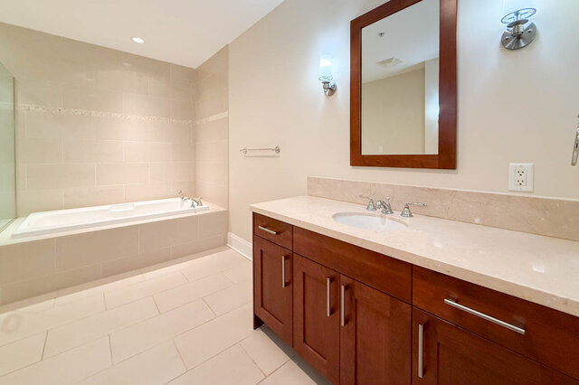 Spacious bathroom with marble countertops and wooden cabinets. - 301-605 Clyde Ave, West Vancouver