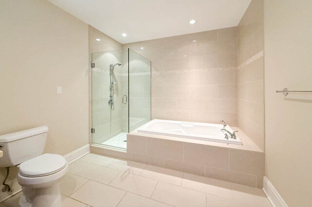 Spacious bathroom with walk-in shower and built-in tub, modern fixtures, and neutral tile walls. - 301-605 Clyde Ave, West Vancouver
