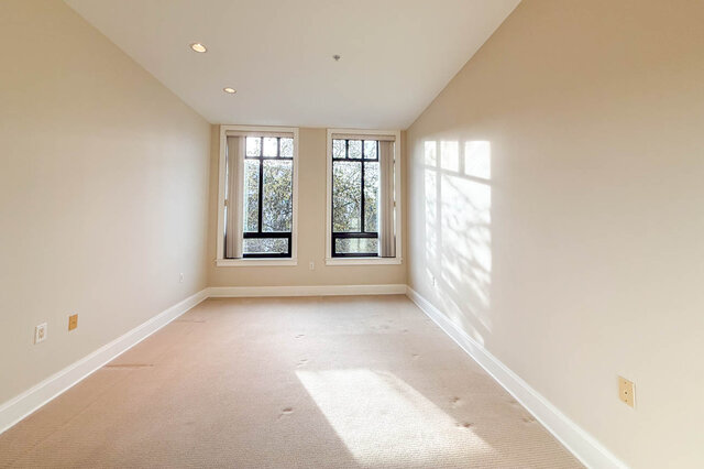Spacious den with carpeted floor, large windows, and natural light. - 301-605 Clyde Ave, West Vancouver