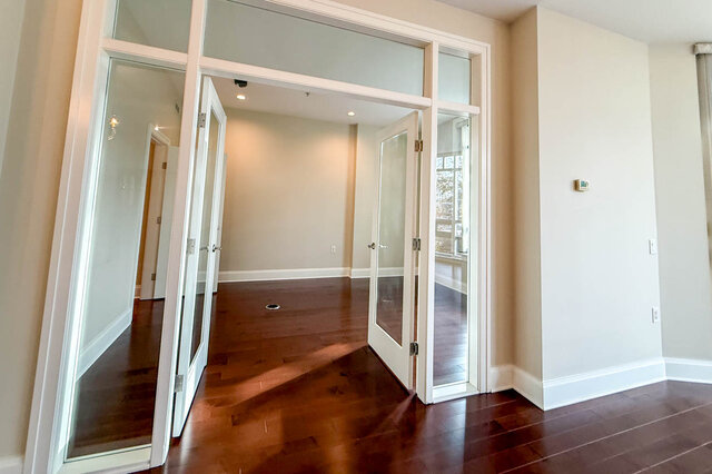 Spacious living room with hardwood floors and a large sliding glass door leading to a balcony. - 301-605 Clyde Ave, West Vancouver