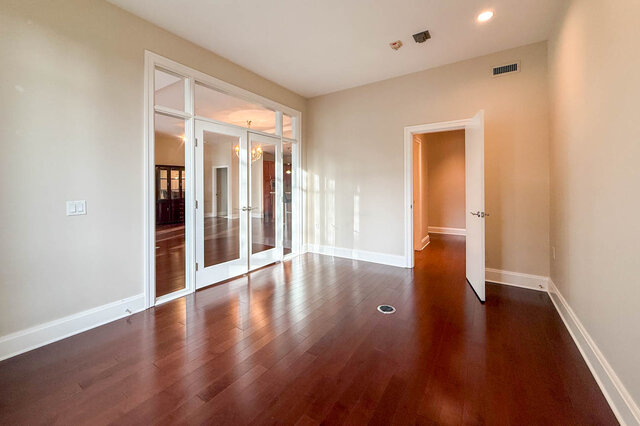 Spacious living room with hardwood floors and French doors leading to another room. - 301-605 Clyde Ave, West Vancouver