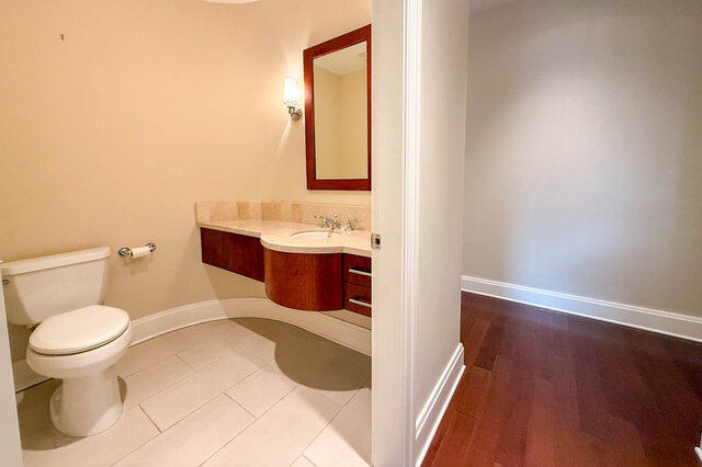 Spacious bathroom with a curved vanity, hardwood floors, and a modern design. - 301-605 Clyde Ave, West Vancouver