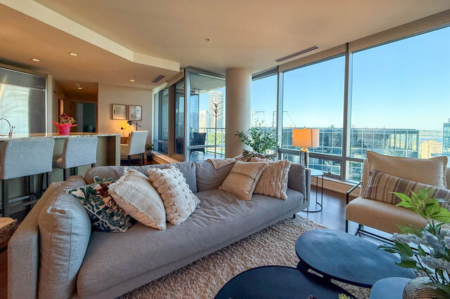 Living room with plush gray sofa and panoramic city views through floor-to-ceiling windows. - 3309-1111 Alberni Street, Vancouver Downtown