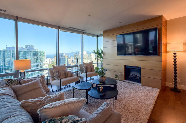 Living room with floor-to-ceiling city views and sleek wooden accent wall. - 3309-1111 Alberni Street, Vancouver Downtown