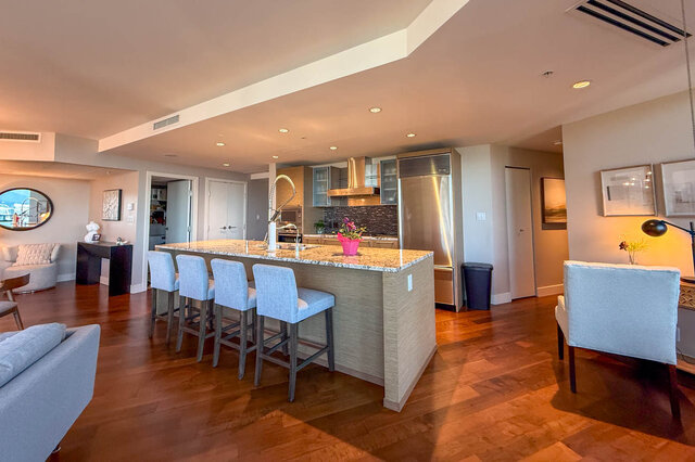 Modern kitchen with granite countertops and blue bar stools over rich hardwood floors. - 3309-1111 Alberni Street, Vancouver Downtown
