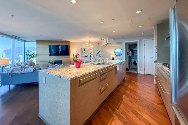 Modern open-concept kitchen featuring granite countertops, hardwood floors, and panoramic city views. - 3309-1111 Alberni Street, Vancouver Downtown