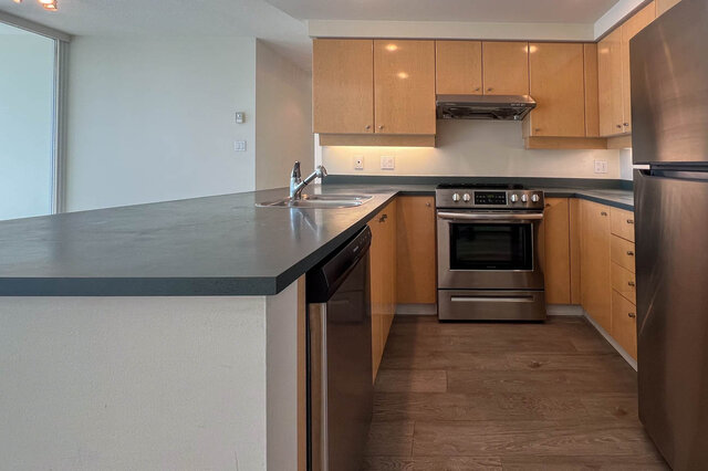 Bright kitchen with modern stainless steel appliances, hardwood floors, and a large island. - 2905-1009 Expo Boulevard, Vancouver Downtown