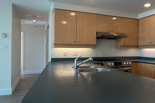 Modern kitchen with dark countertops and stainless steel appliances, featuring a sleek island and ample cabinetry.