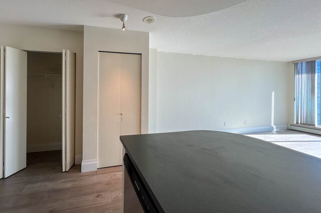 Bright kitchen with modern countertops and hardwood floors, open to a spacious living area with a city view.