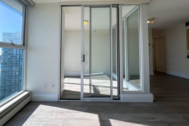 Spacious living room with hardwood floors, large windows, and a sliding glass door leading to a balcony.