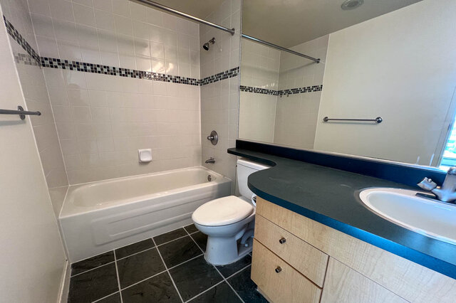 Spacious bathroom with a modern vanity, dark countertop, and a bathtub/shower combo. - 2905-1009 Expo Boulevard, Vancouver Downtown