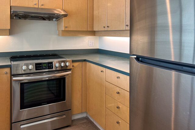 Bright kitchen with stainless steel appliances, light wood cabinets, and dark green countertops. - 2905-1009 Expo Boulevard, Vancouver Downtown
