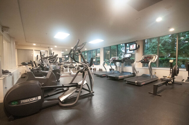 Spacious, well-lit gym with large windows, cardio machines, and a serene outdoor view. - 2905-1009 Expo Boulevard, Vancouver Downtown
