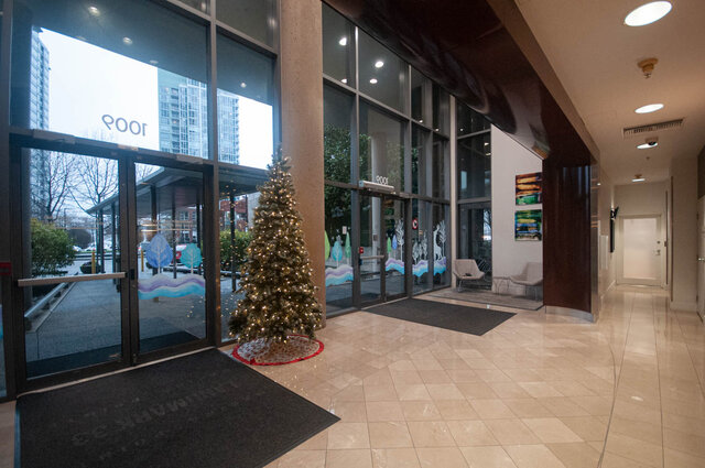 Festively decorated entrance with a Christmas tree and holiday-themed window decals, leading to a modern 2-bedroom + den...
