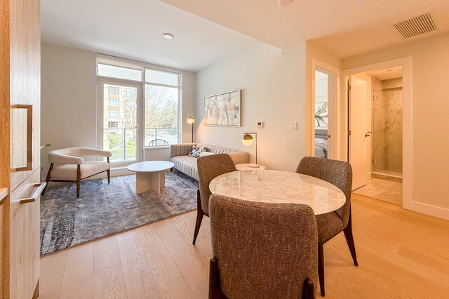 Spacious living room with hardwood floors, modern furniture, and large windows offering a city view. - 203-423 6th Street, West Vancouver