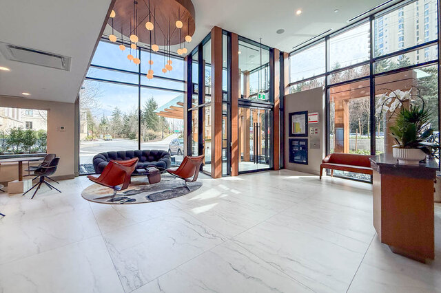 Spacious living room with marble floors, modern furniture, and large windows offering a city view. - 203-423 6th Street, West Vancouver