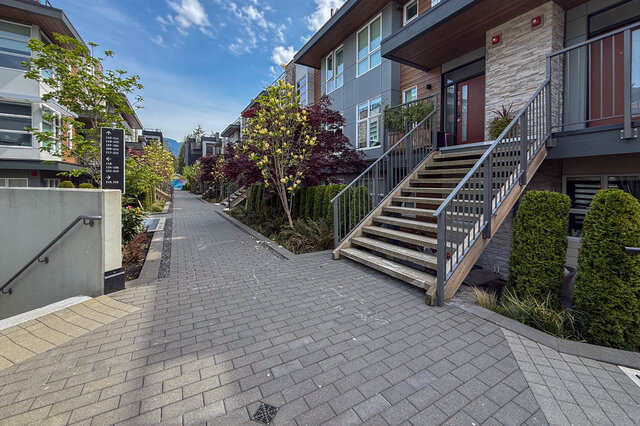 Modern bathroom with marble tiles and a sleek black countertop. - 210-2060 Curling Road, North Vancouver