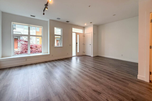 Bright laundry room with stacked white Whirlpool washer and dryer. - 210-2060 Curling Road, North Vancouver