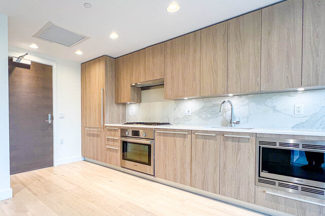 Bright kitchen with sleek marble countertops and warm hardwood flooring. - 309-2738 Library Lane, North Vancouver