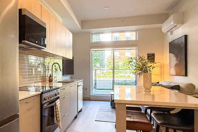 Bright open-concept kitchen with light wood cabinets, white subway tile, and a dining table beside a large window.