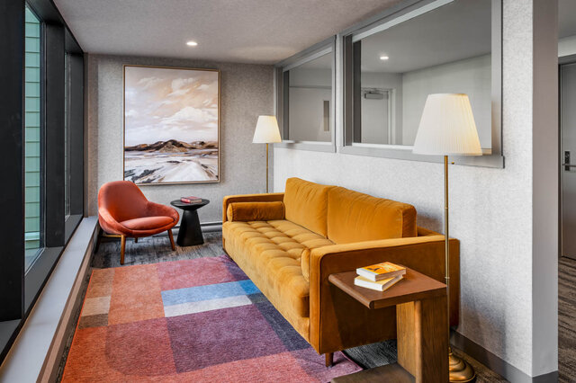 Cozy living area featuring a mustard velvet sofa, coral accent chair, and a colorful patchwork rug. - 115-1529 Oxford Street, North Vancouver
