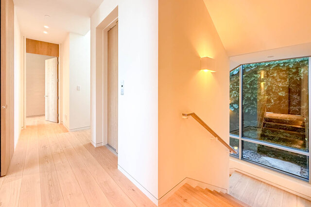 Modern hallway with light wood floors and a large window overlooking greenery. - 2390 Westhill Drive, West Vancouver
