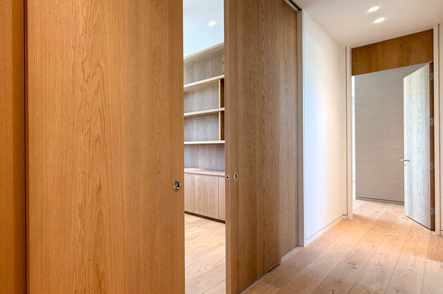 Hallway with light hardwood floors and wooden sliding doors. - 2390 Westhill Drive, West Vancouver