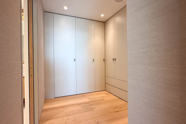 Walk-in closet with built-in white cabinets and light wood flooring. - 2390 Westhill Drive, West Vancouver