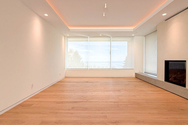Spacious living room with hardwood floors and large window overlooking water. - 2390 Westhill Drive, West Vancouver
