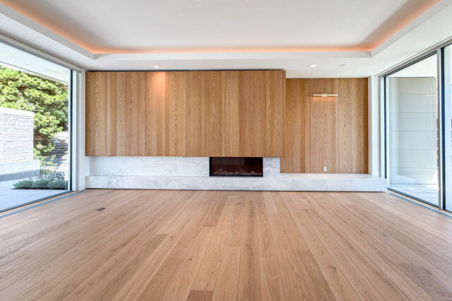 Spacious living room with hardwood floors and a modern wood-walled fireplace. - 2390 Westhill Drive, West Vancouver