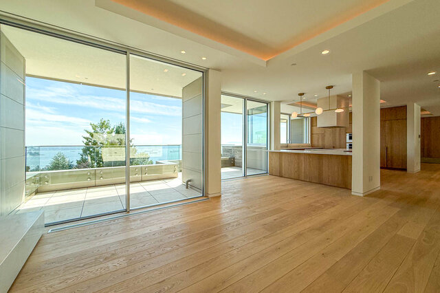 The living room has hardwood floors and floor-to-ceiling sliding glass doors that open to a balcony with a water view.