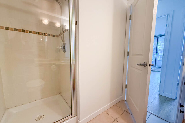 Bathroom with walk-in shower, glass door, and decorative tile border. - 1805-4388 Buchanan Street, Burnaby
