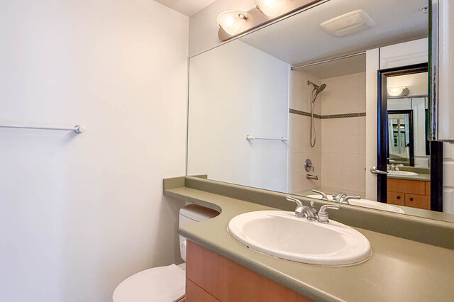 Spacious bedroom featuring patterned bedspread and warm hardwood flooring. - 1805-4388 Buchanan Street, Burnaby